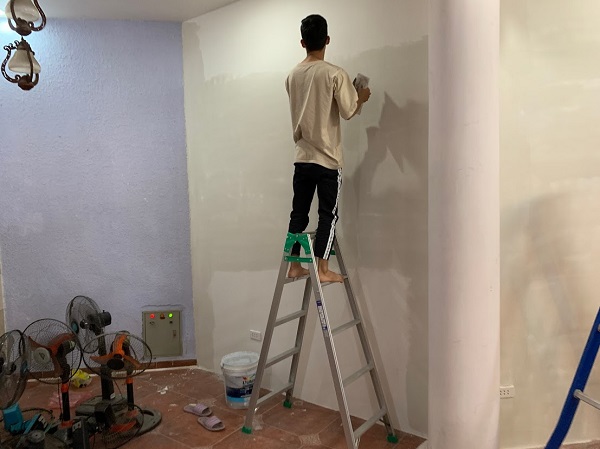 Thợ dùng thang để sơn tường
